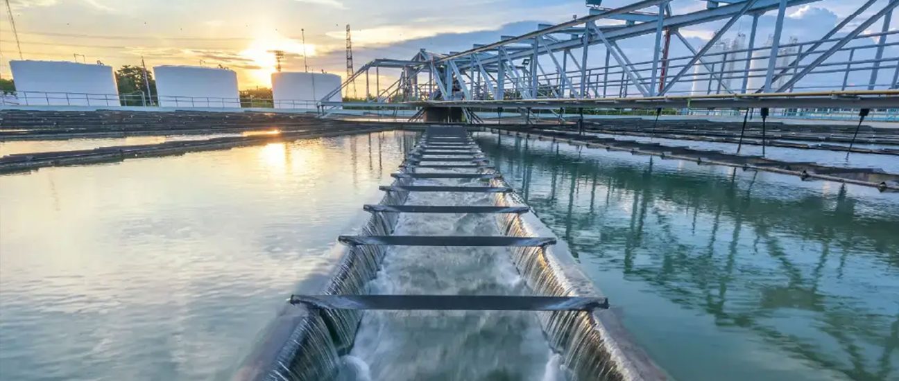 Water flowing through a central weir channel in an outdoor water treatment facility at sunset