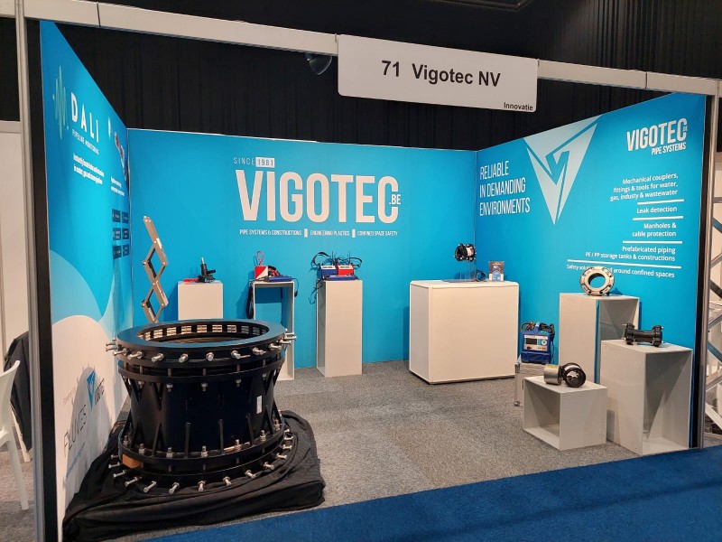 Vigotec exhibition stand featuring blue branded backdrops and displays of industrial pipe systems and equipment