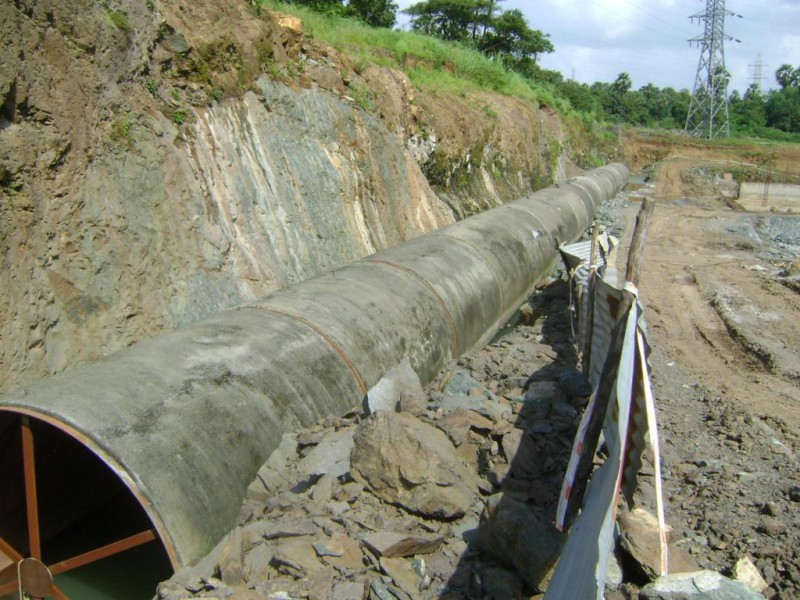 Large pipeline laid in an excavated trench along a rocky hillside at a construction site