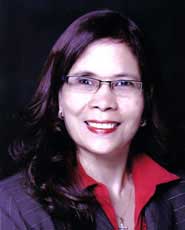 Smiling woman with long dark hair, wearing glasses and a red collared shirt under a dark jacket