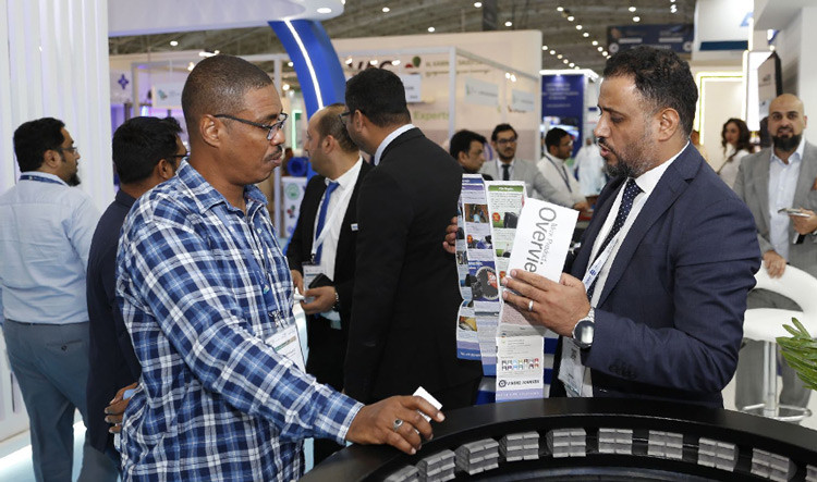 An exhibitor presenting a product overview brochure to a visitor at a trade show