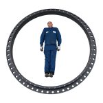 A man in blue overalls standing inside a large industrial slewing bearing ring to demonstrate its scale
