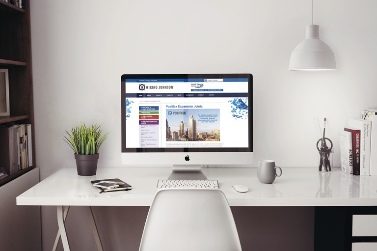 Desktop computer monitor displaying the Viking Johnson website on a white desk