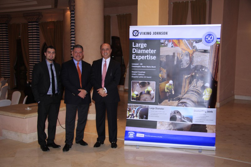 Three men in suits standing next to a Viking Johnson corporate presentation banner