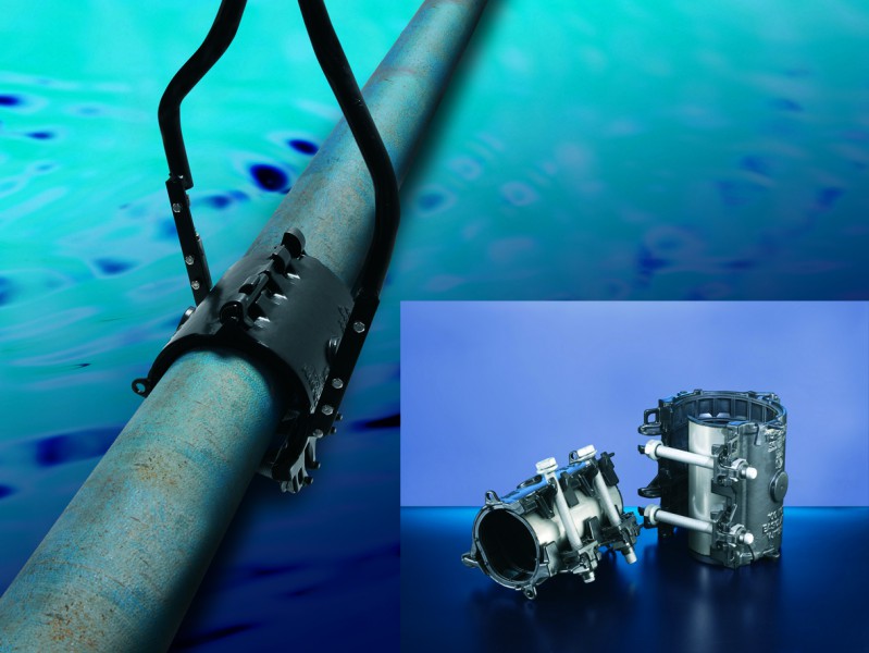 Subsea pipe clamp tool attached to an underwater pipe, with an inset showing two pipe repair clamps