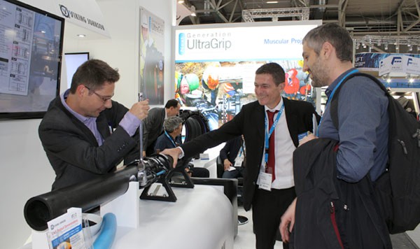 A representative demonstrating pipe fittings to two visitors at a Viking Johnson trade stand