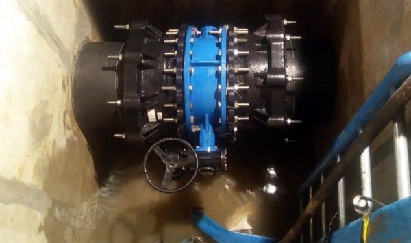 Large blue flanged valve installed on a pipe inside a concrete pit