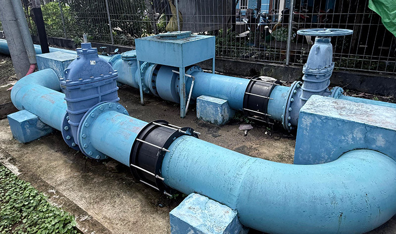 Large blue water pipes fitted with control valves and couplings mounted on concrete blocks