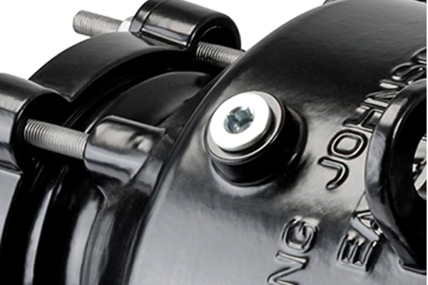 Close-up of a black metal pipe coupling showing threaded bolts and a silver hex socket plug
