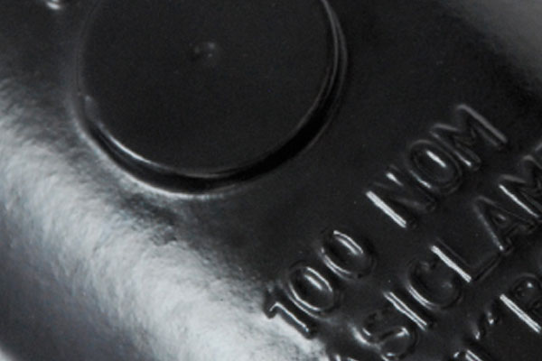 Embossed text reading 100 NOM on a black plastic surface