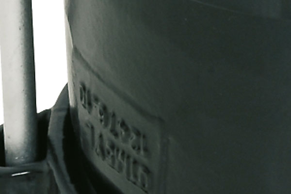Close-up of embossed part numbers on a dark moulded plastic component next to a metal pin