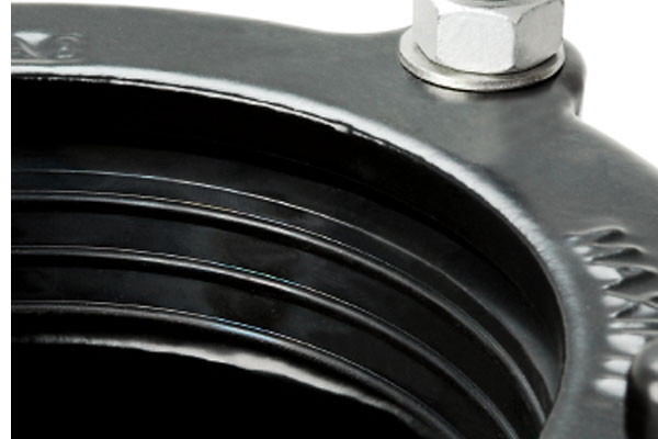 Close-up of a black rubber pipe seal showing internal ribs and a bolted flange