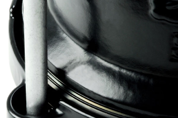 Close-up of a glossy black ceramic pot with a metal handle inserted into a side loop