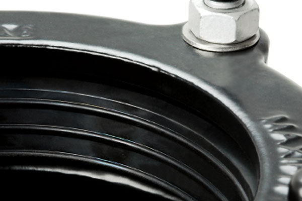 Close-up of a ribbed black rubber pipe coupling with a top securing bolt and washer