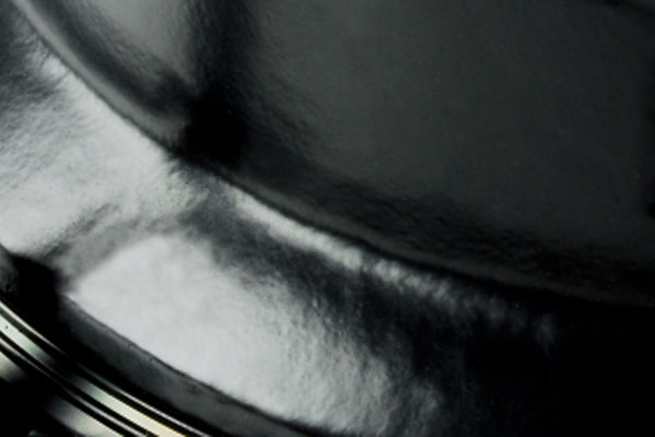 Close-up of a curved, reflective black metallic surface with soft light highlights