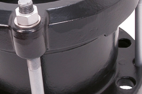 Close-up of a black metal pipe coupling with threaded tie rods and nuts