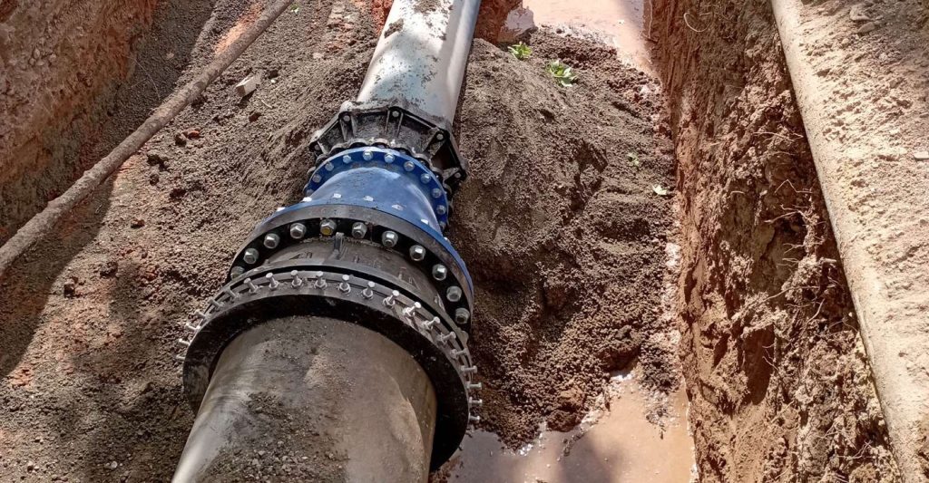 Large pipe connected with a bolted blue flange joint in an excavated trench