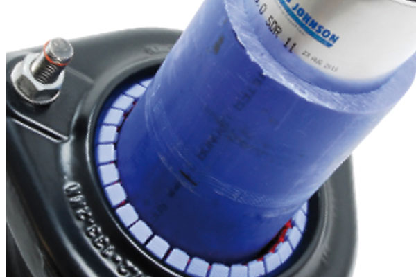 Blue pipe fitted into a black mechanical flange assembly with modular sealing segments and a mounting bolt