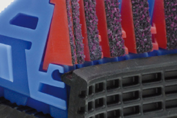 Extreme close-up of a multi-layered razor head showing coloured plastic supports, textured strips, and a black rubber guard