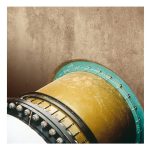 Large industrial cylindrical pipe with a teal bolted flange entering a textured concrete wall