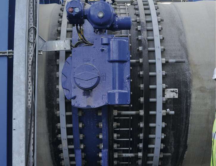 Large blue motorized valve actuator mounted on a heavy industrial pipe flange secured with bolts