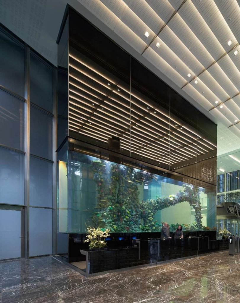 The reception area of Heron Tower featuring a massive built-in aquarium behind the reception desk