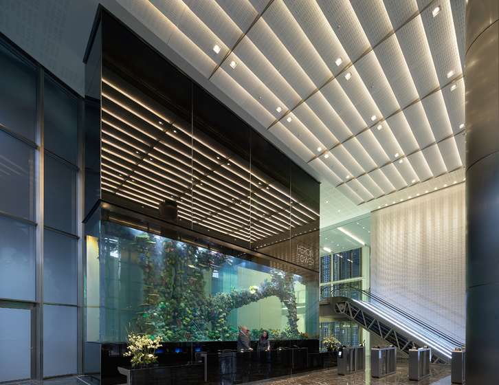 Modern lobby of Heron Tower featuring a massive aquarium behind the reception desk, with an escalator in the background