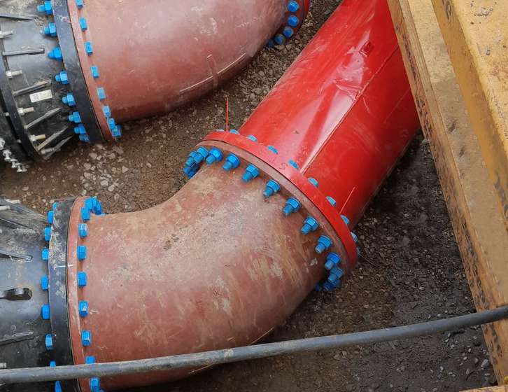 Large industrial pipes connected at flanged joints with blue bolts