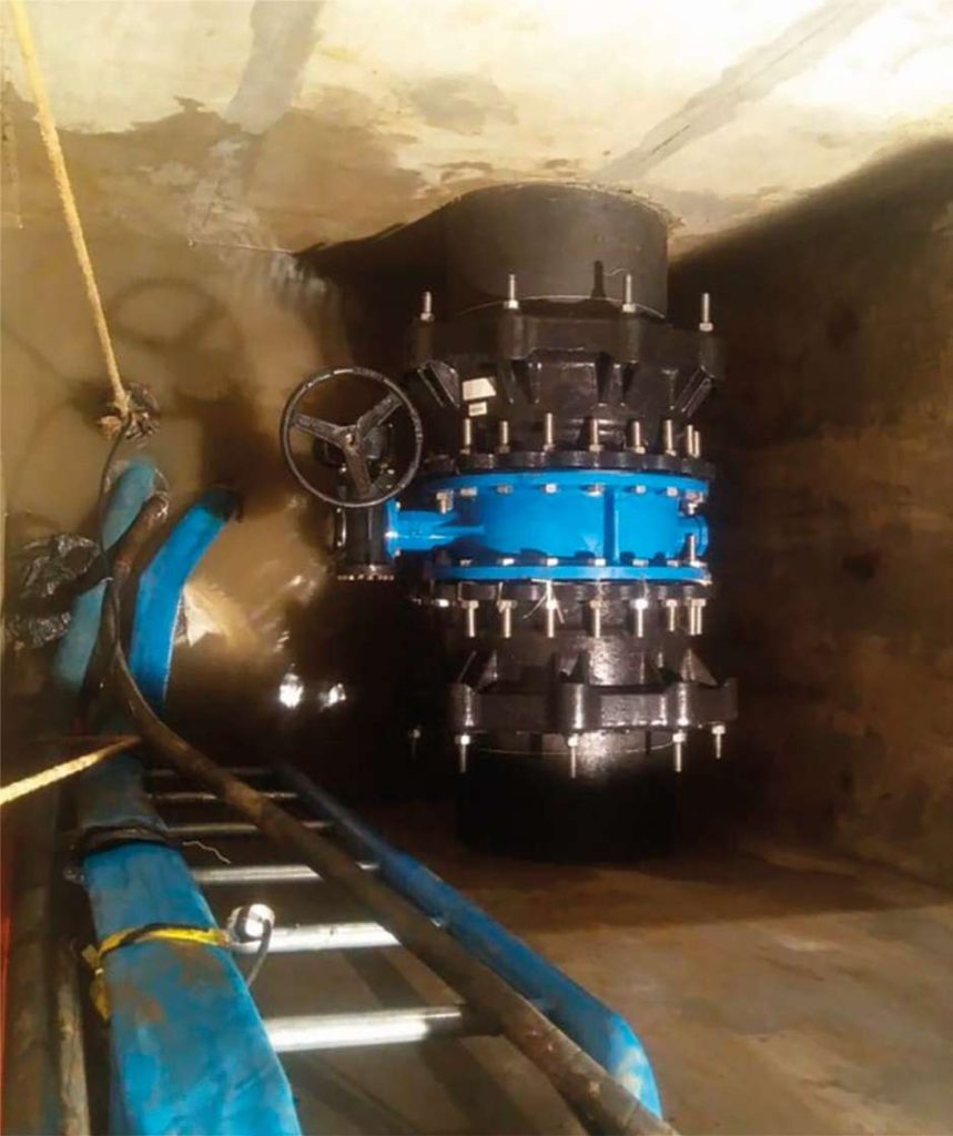 Large industrial pipe valve with handwheel installed vertically inside a concrete chamber