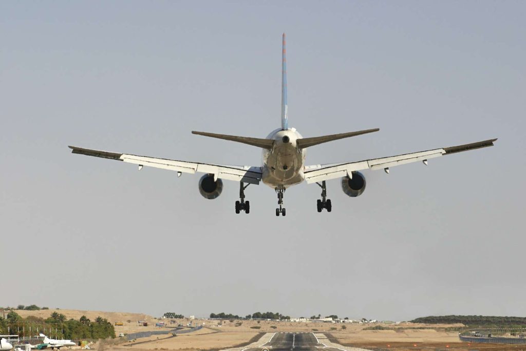 Rear view of a commercial aeroplane on final approach to a runway with landing gear deployed
