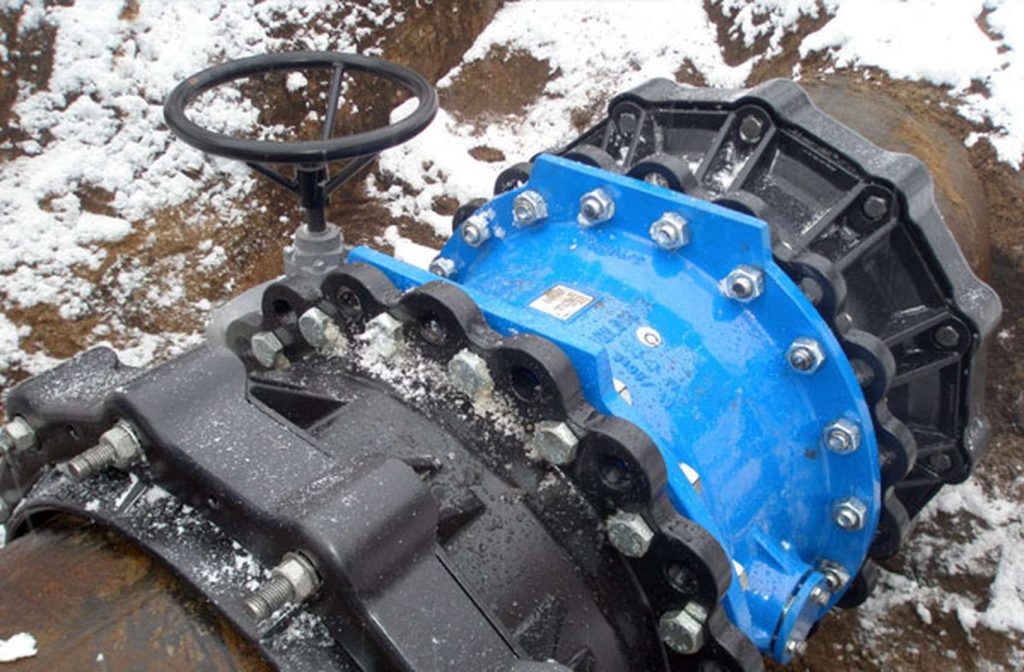 Heavy-duty industrial pipe valve and flange assembly with a handwheel, installed outdoors in snowy ground