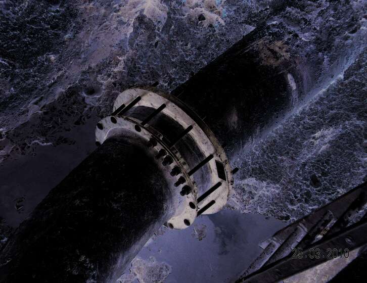 Large industrial pipe with a flanged coupling over turbulent water