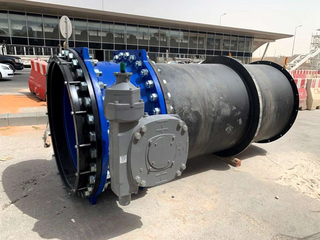 Large blue and black industrial pipe valve with attached grey gearbox resting on a paved surface