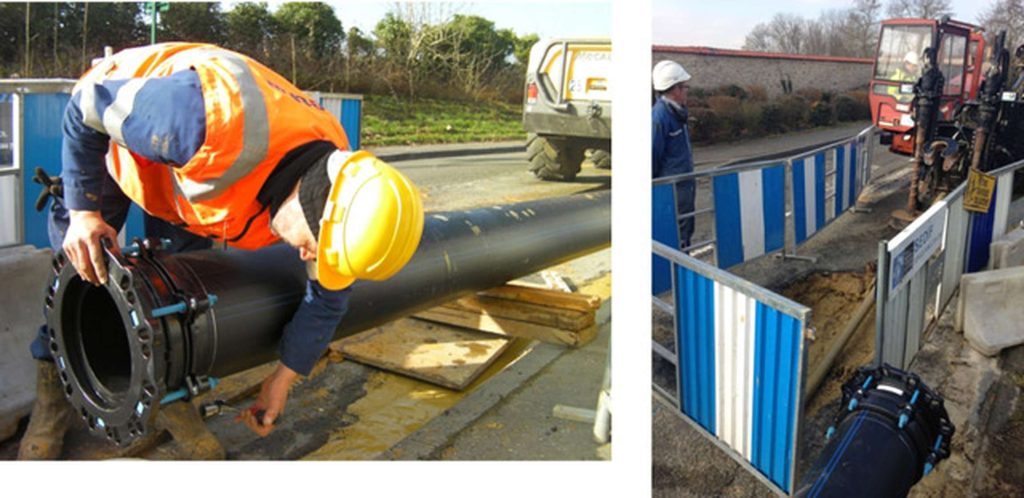 A construction worker fitting a flange on a large pipe alongside a view of a trench at a roadworks site