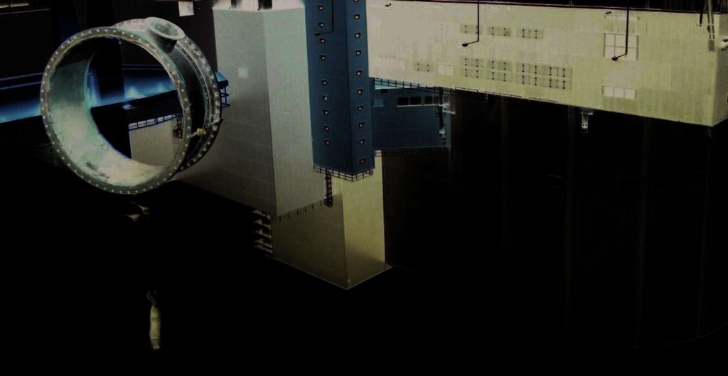 A large metal spacecraft module mock-up suspended inside a deep neutral buoyancy training pool